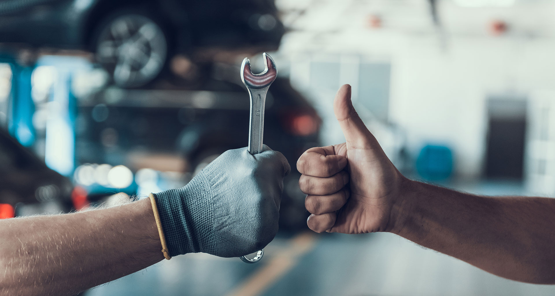 équipe pgla-garage-lussan à Lussan échangeant un pouce levé lors d’une réparation automobile en atelier