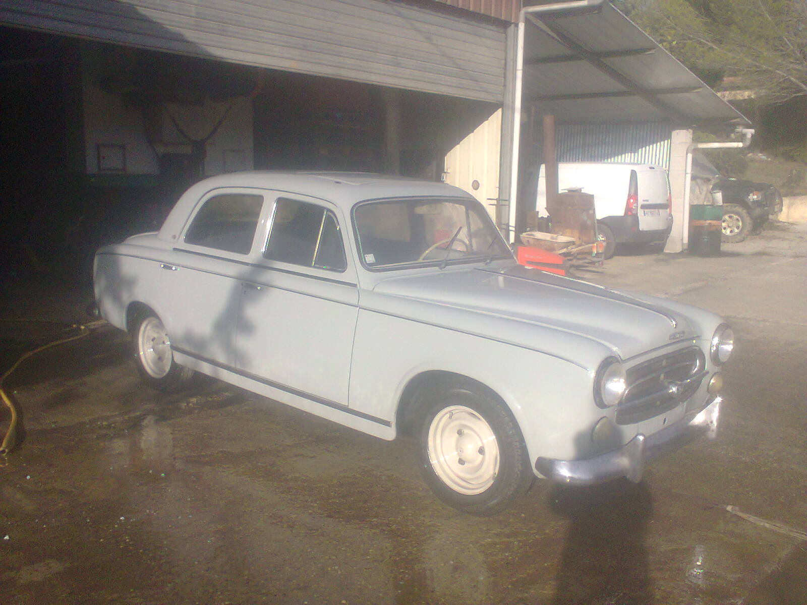 voiture ancienne devant pgla-garage-lussan à Lussan sur sol mouillé, ambiance rétro d’atelier mécanique